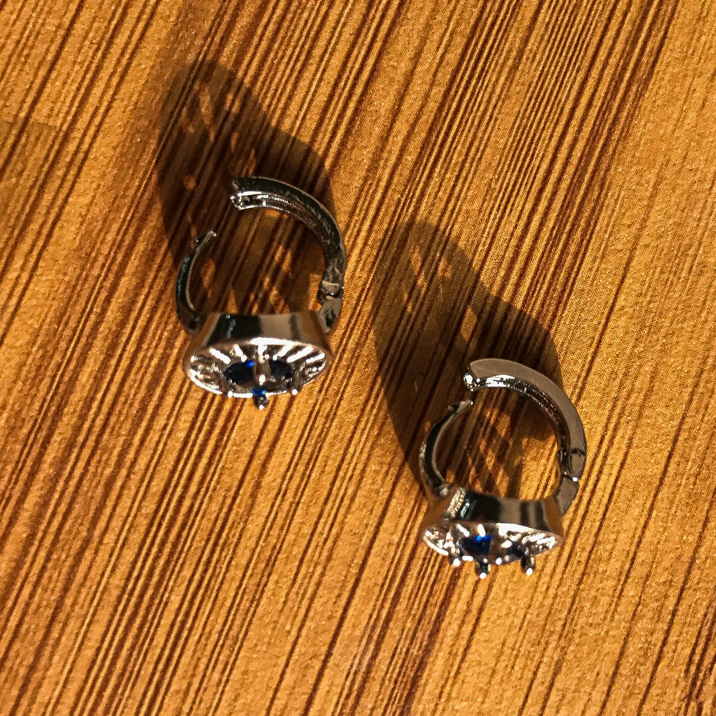 Two silver-colored stud earrings shaped like arc reactors, each with a blue crystal in the center.