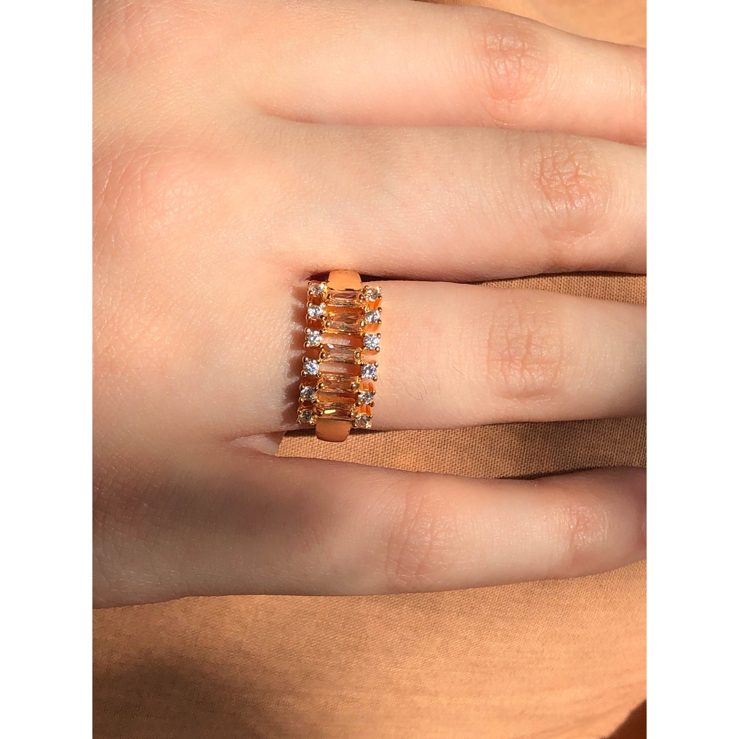 A close-up of a glittering ring featuring a large central clear stone and a band entirely covered in multiple rows of smaller clear sparkling stones.