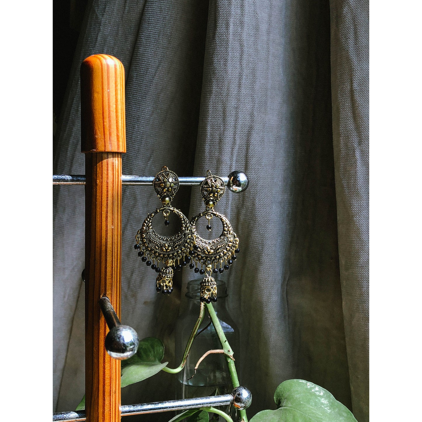A pair of ornate silver-tone chandbali jhumka earrings featuring a crescent moon design at the top with intricate patterns and a dangling bell-shaped jhumka at the bottom.