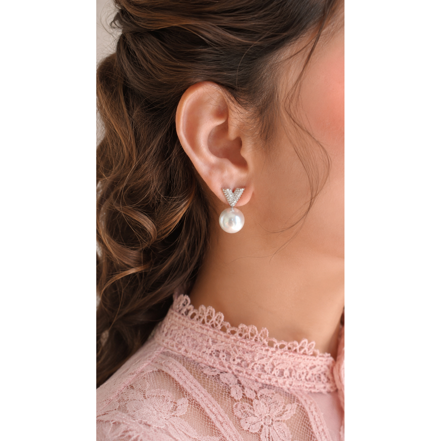 Close-up of a person wearing pearl earrings with a blurred background