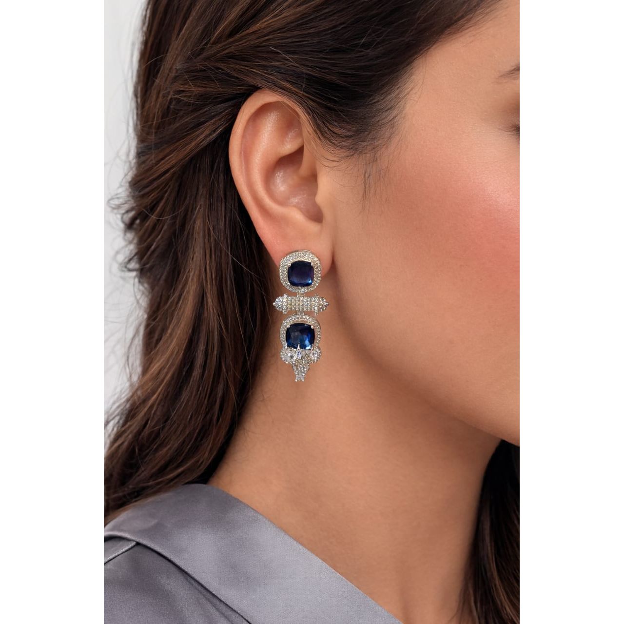 Woman wearing blue cushion-cut luxury statement drop earrings in silver-tone finish