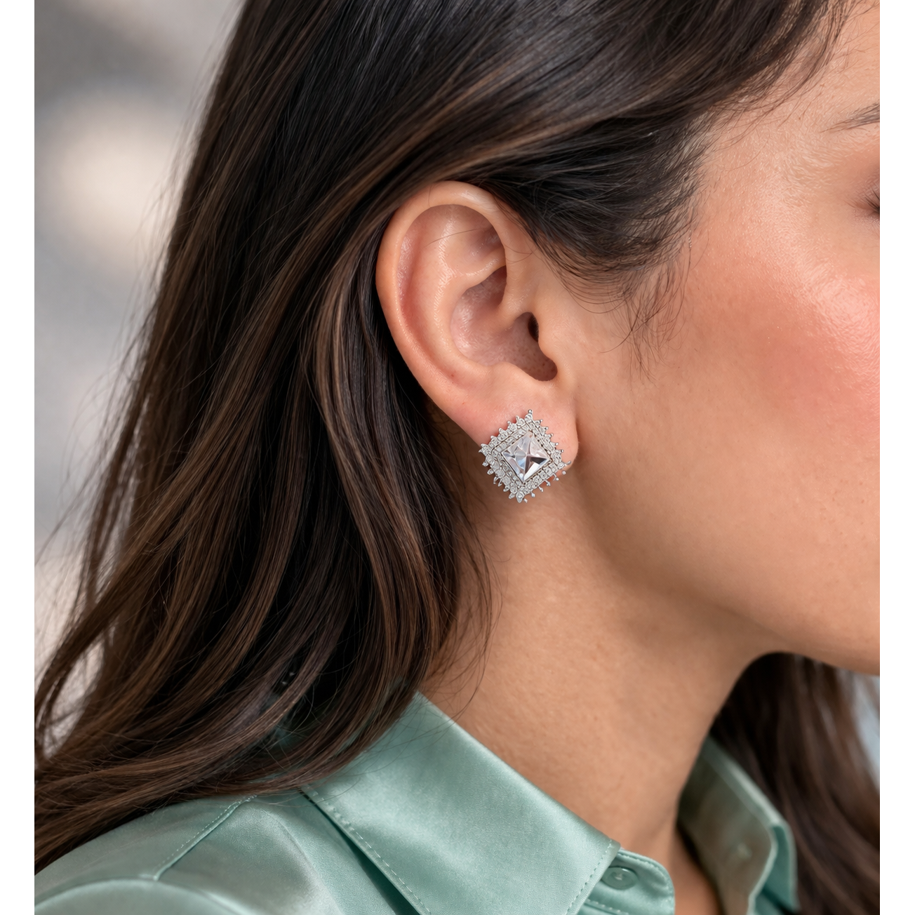 Silver square crystal stud earrings with halo detailing worn on ear side profile with sea green silk shir