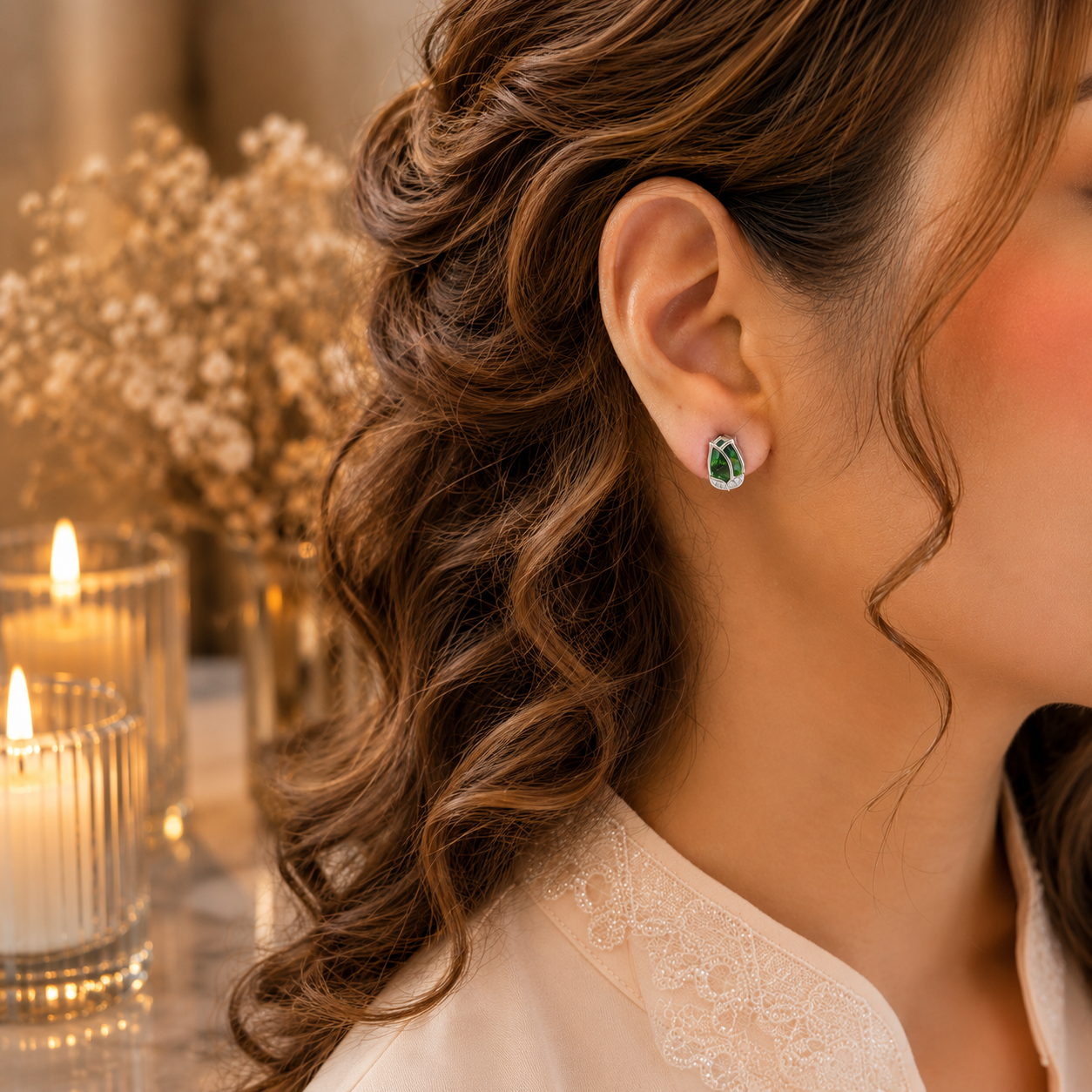 Woman wearing tulip crystal stud earrings in a luxury close-up portrait with soft curls, ivory-peach outfit, warm candlelight and dried floral background