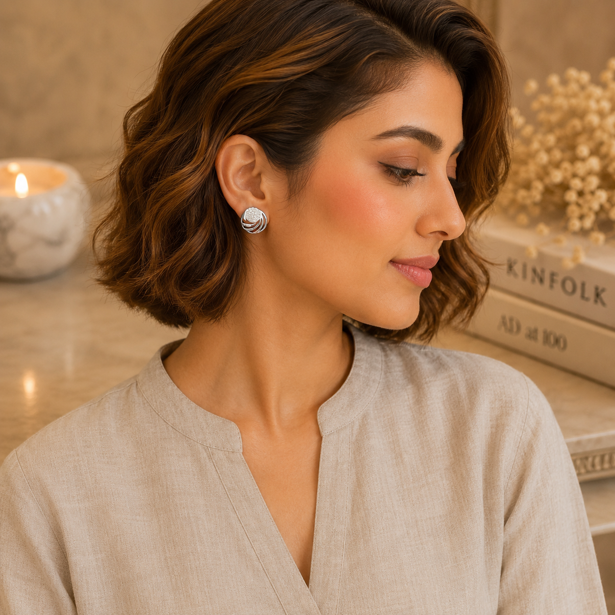 Woman wearing silver swirl crystal stud earrings with polished silver finish and sparkling zircon stones, styled with a greige linen outfit for a modern everyday jewellery look