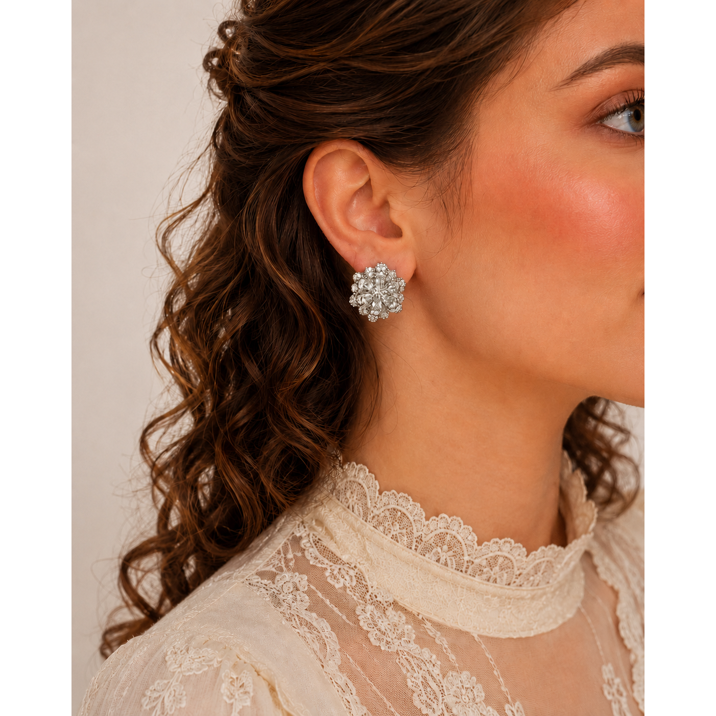 Silver floral crystal stud earrings worn by model with lace ivory blouse, sparkling flower design statement earrings close-up