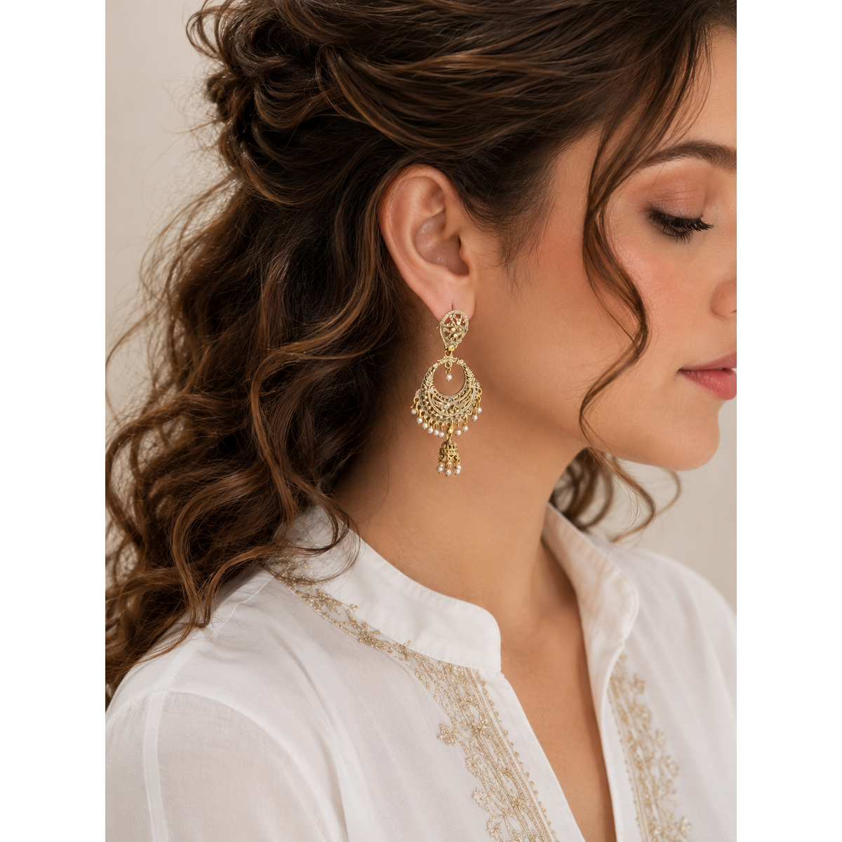 Woman wearing antique gold Chandbali earrings with ivory pearl tassels, traditional statement jewelry with intricate filigree detailing.