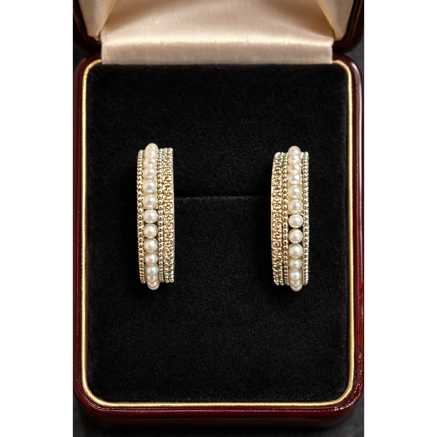 Pair of pearl row multi-band hoop earrings displayed inside a black velvet jewelry box showing layered design and beadwork texture