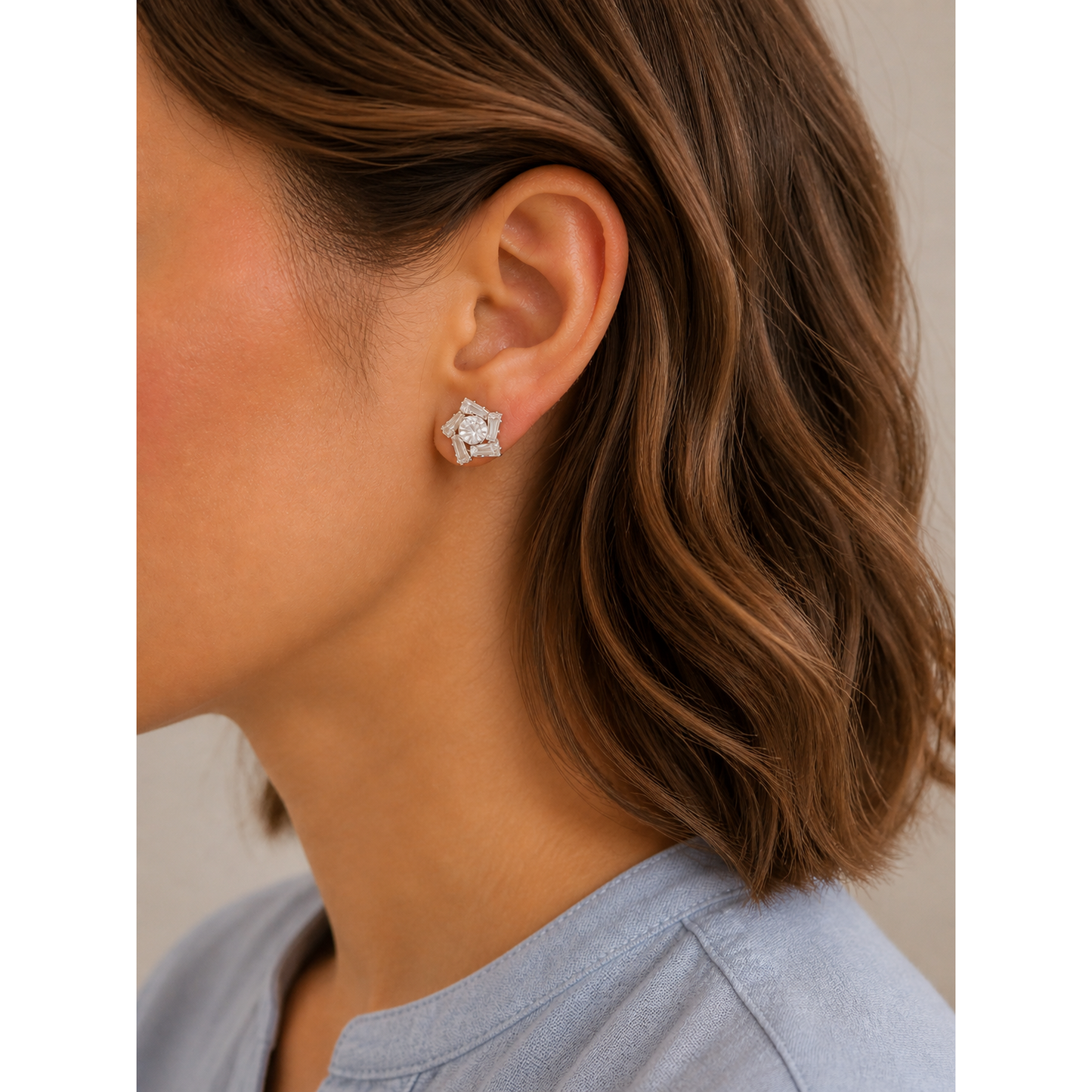 Silver geometric crystal stud earrings worn on ear with short brown wavy hair side profile close-up