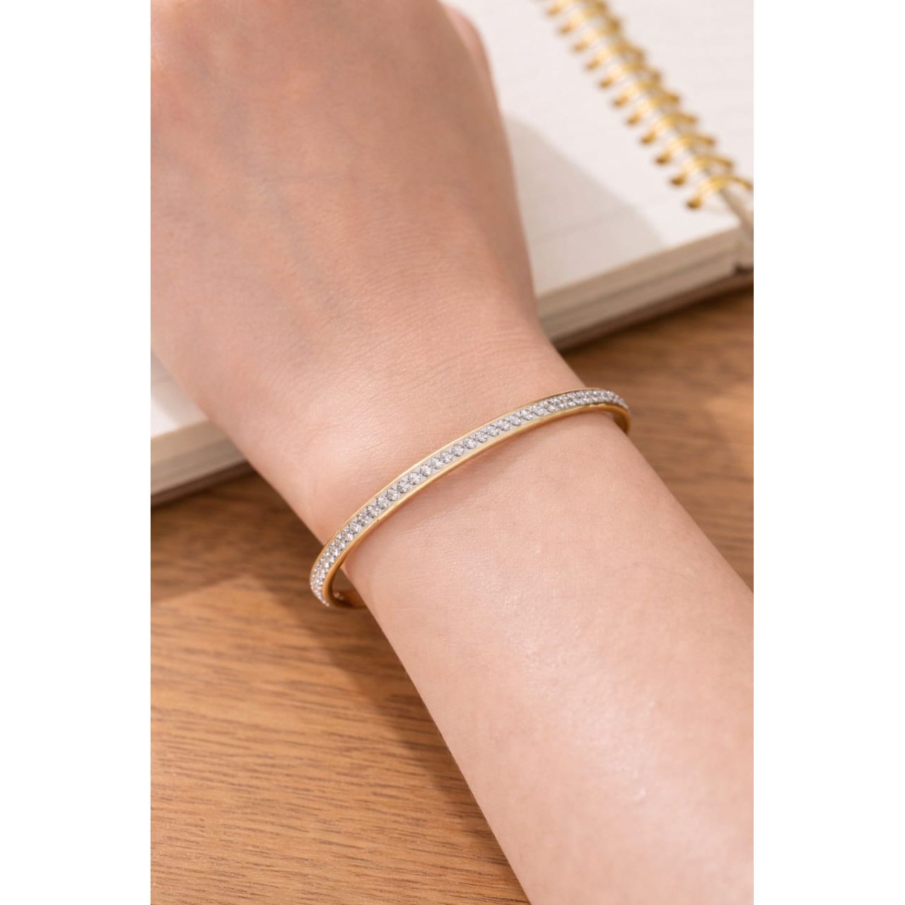 Gold crystal bracelet worn on wrist with slim band and single row of round stones for everyday wear styling