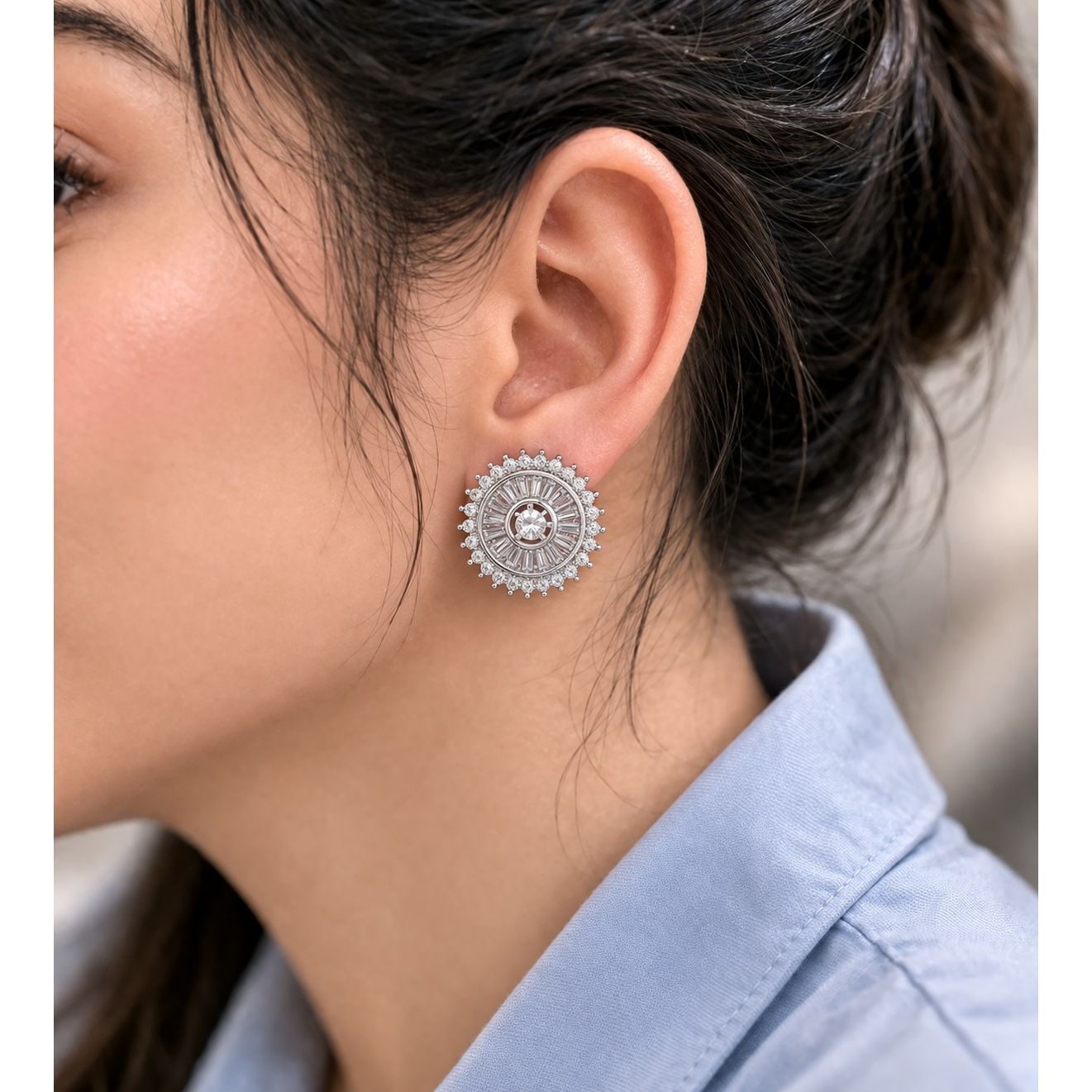 Silver sunburst stud earrings with crystal center worn on ear close-up side profile