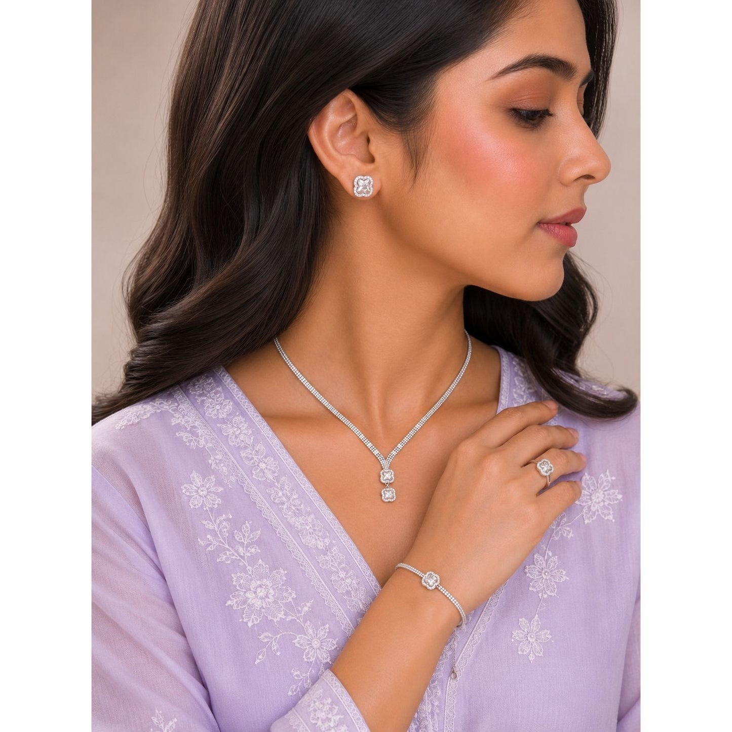 Model wearing a silver clover crystal jewelry set featuring matching stud earrings, double-drop pendant necklace, statement ring, and bracelet with sparkling faceted stones.
