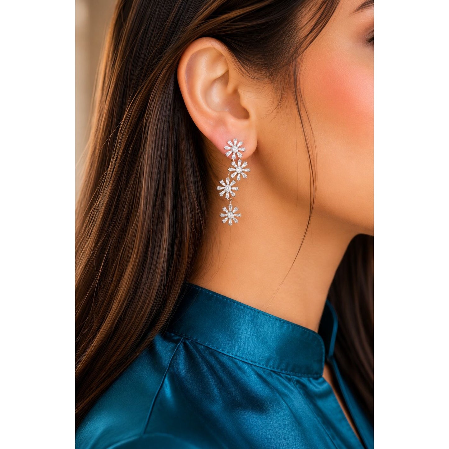 Silver floral cubic zirconia drop earrings worn by model with teal satin shirt, featuring four cascading flower motifs.