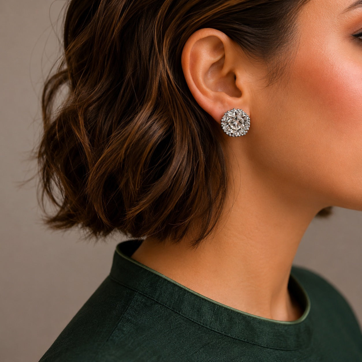 Close-up of a woman wearing a silver earring with a green top against a neutral background