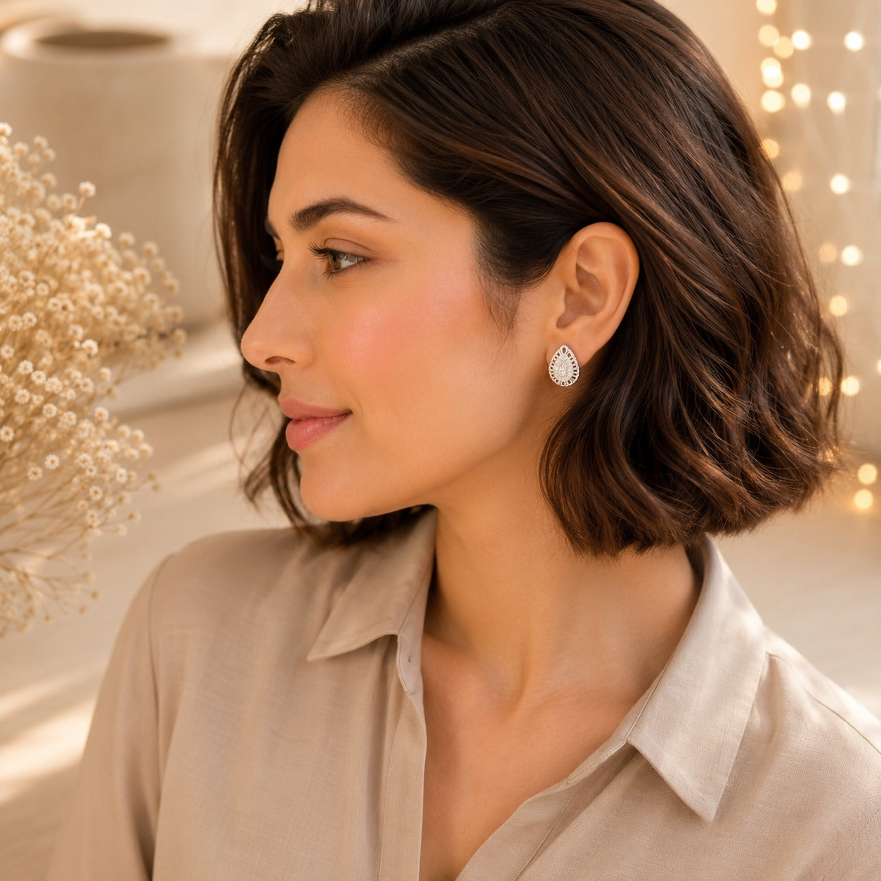 Woman wearing luxury silver teardrop crystal stud earrings with pavé halo in a side profile portrait, showcasing premium everyday jeweller