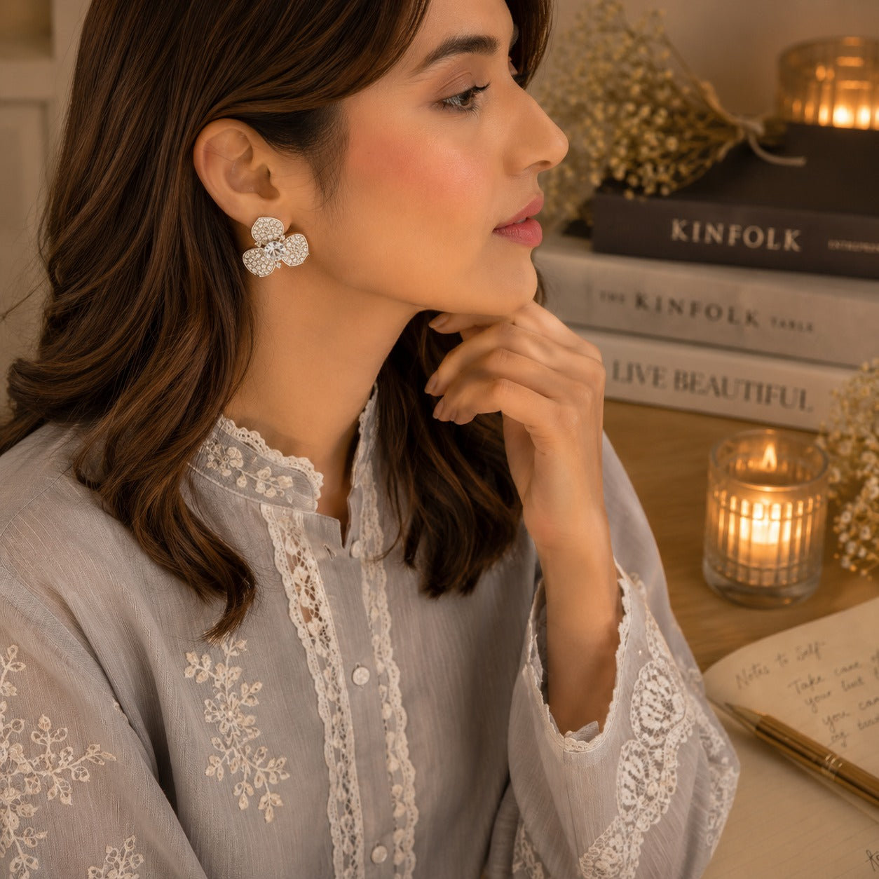 Model wearing silver crystal floral stud earrings with a three-petal pavé design and sparkling center stone in a side-profile portrait.