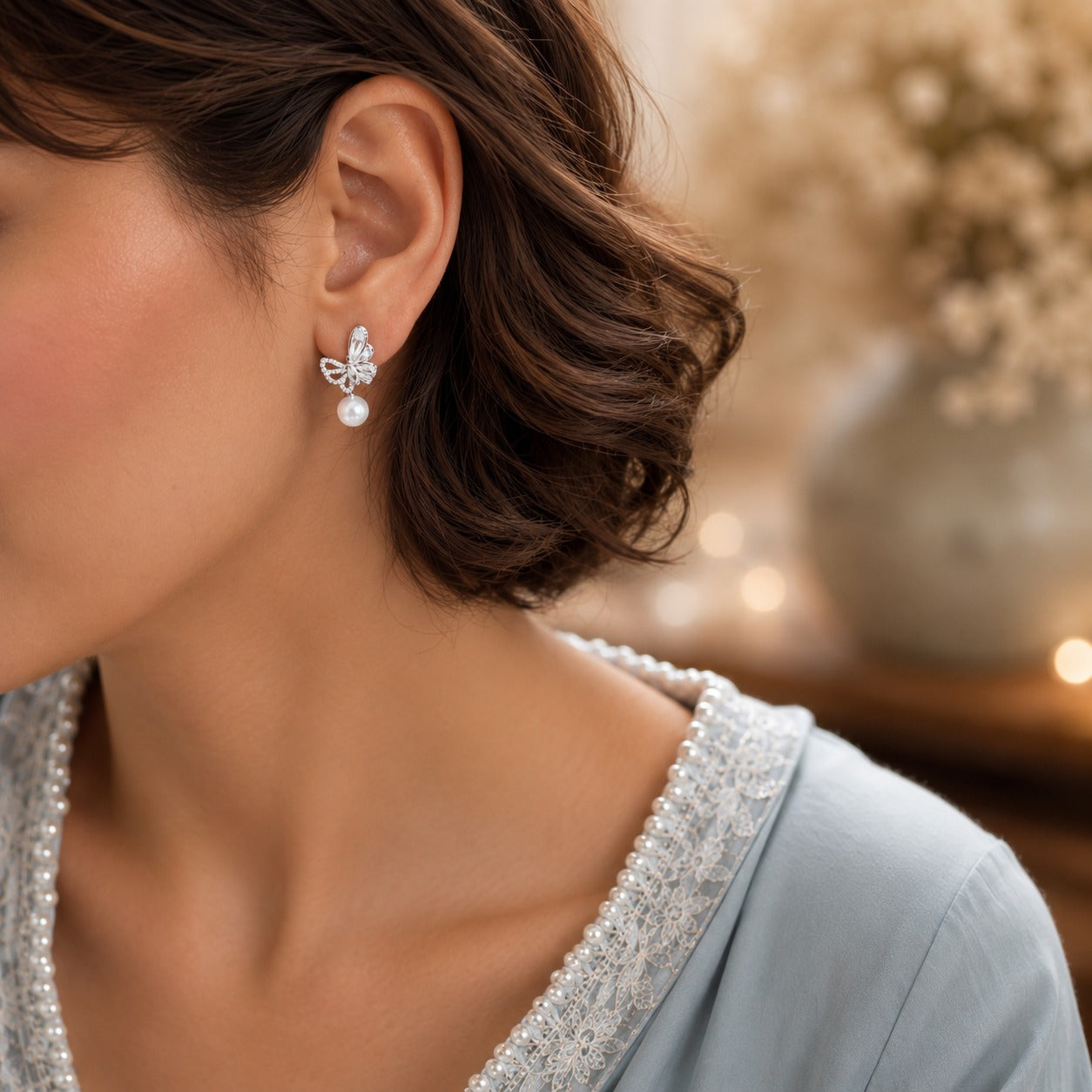 Model wearing elegant silver butterfly pearl drop earrings with sparkling marquise crystals and luminous pearl drops in a refined luxury setting.