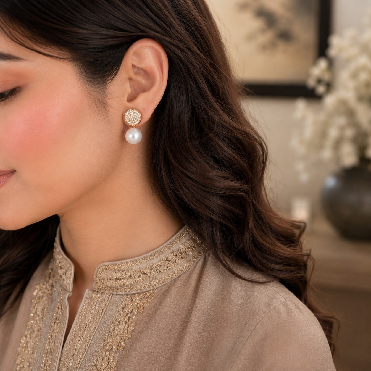 Model wearing elegant gold pavé pearl drop earrings with sparkling crystal tops and luminous white pearl drops in a refined luxury setting.