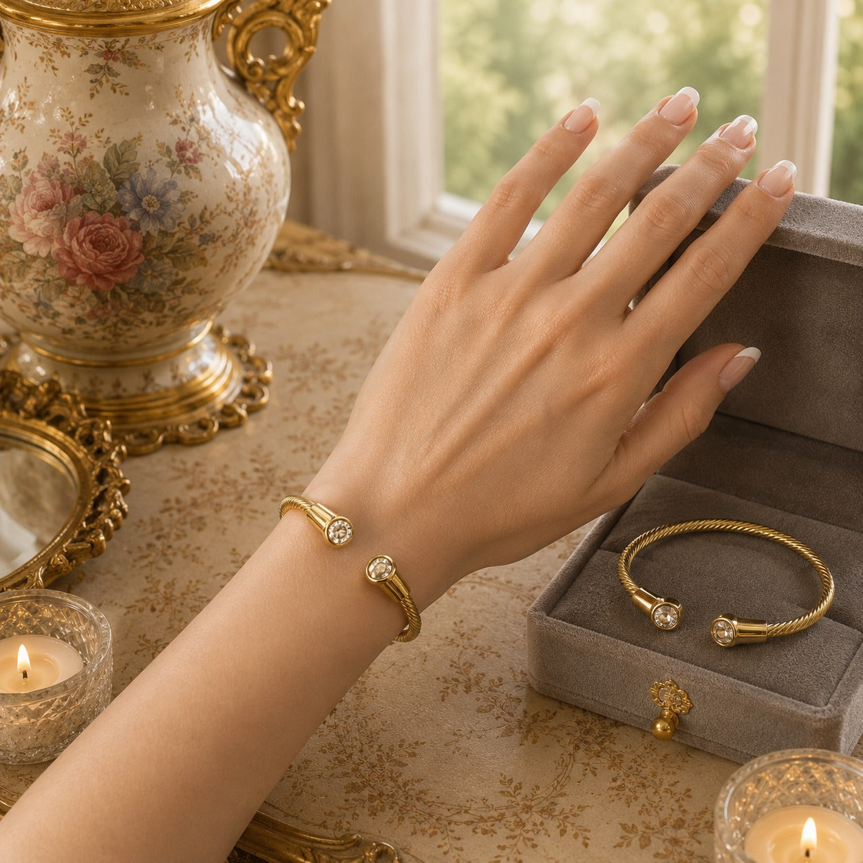 Gold twisted cable cuff bracelet worn on the wrist with matching bracelet displayed in a velvet jewellery box