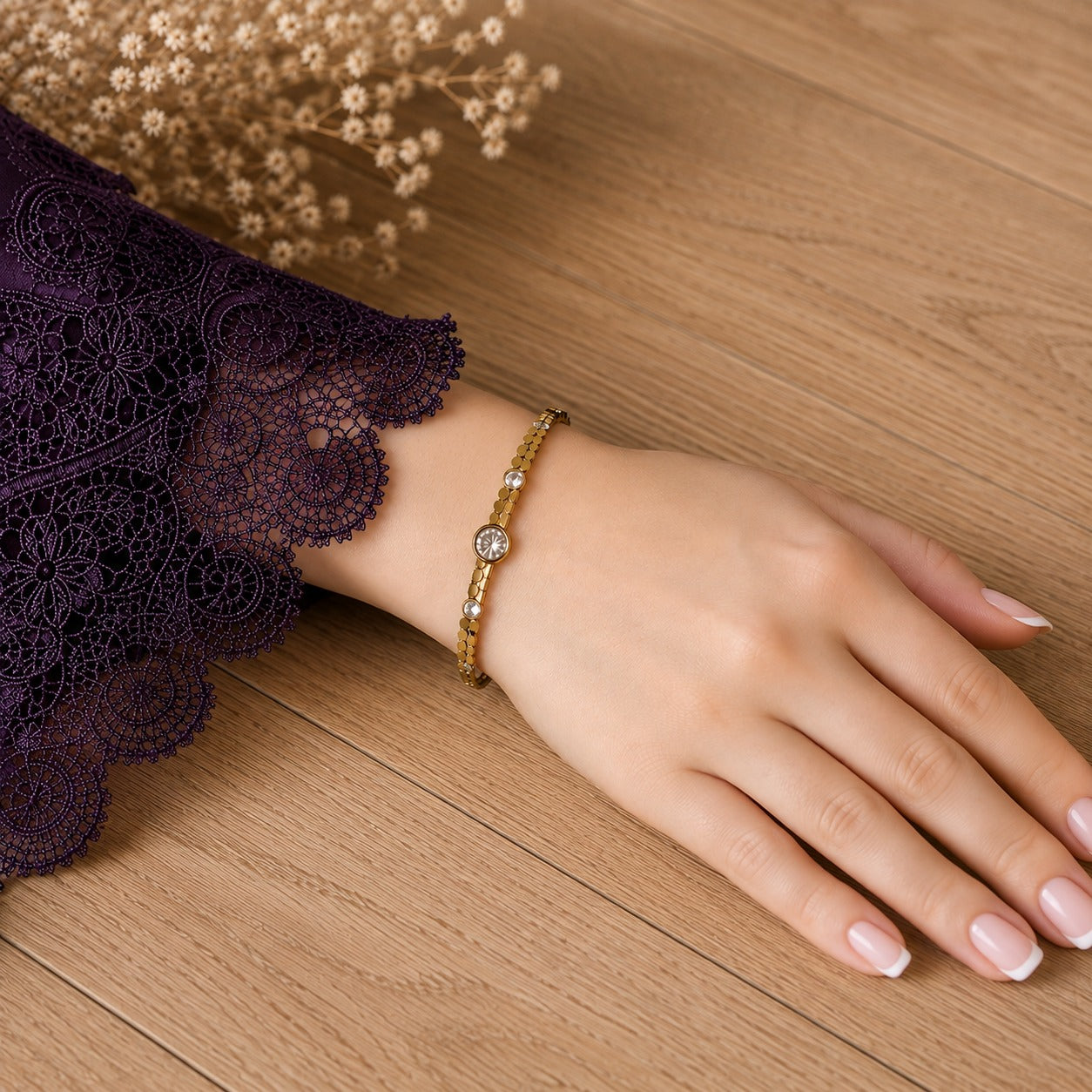 Gold magnetic bracelet worn on a hand with purple lace sleeve