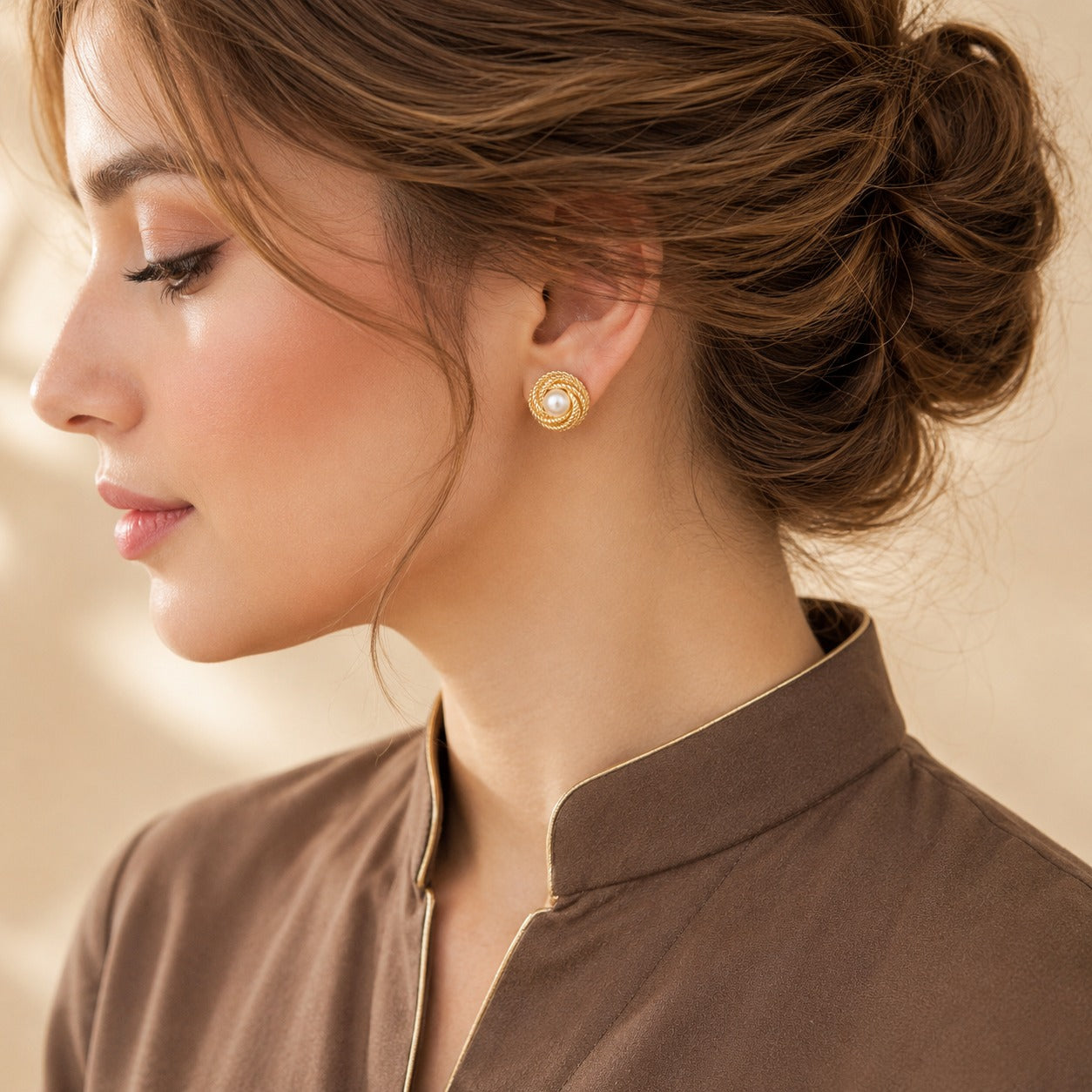 Model wearing round gold-tone Pearl Coil Studs featuring a luminous pearl centre framed by intricate rope-textured c