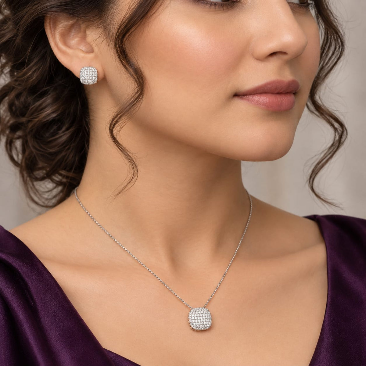 Model wearing rounded-square clear zircon stud earrings with a matching silver-tone zircon pendant necklace