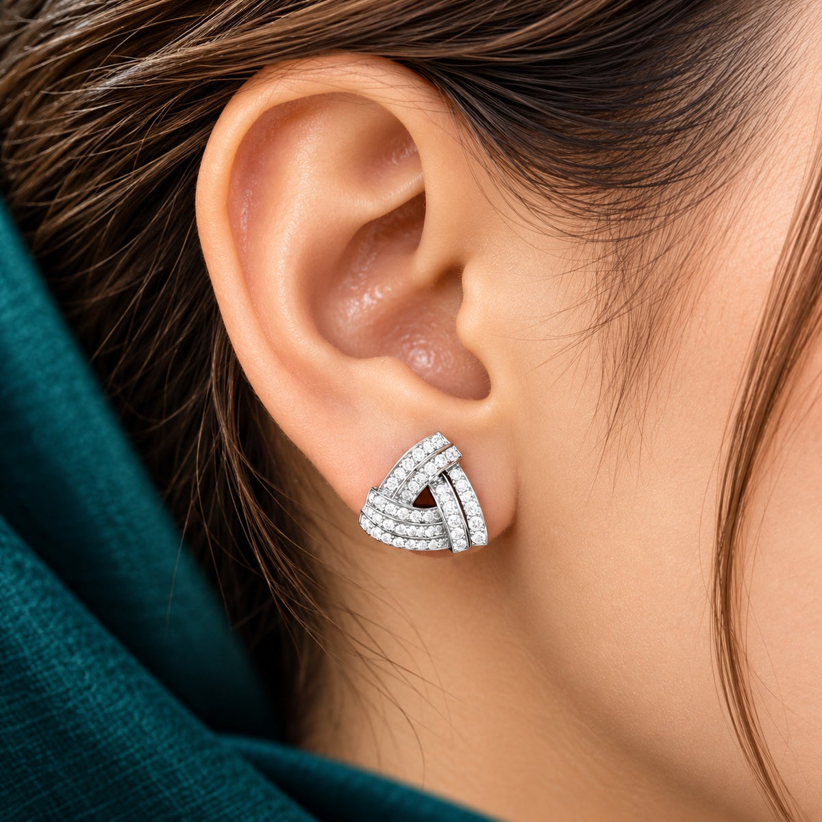 Close-up of a Vela Fold S925 sterling silver stud worn on the ear, showing its layered triangular design and clear zircon detailing