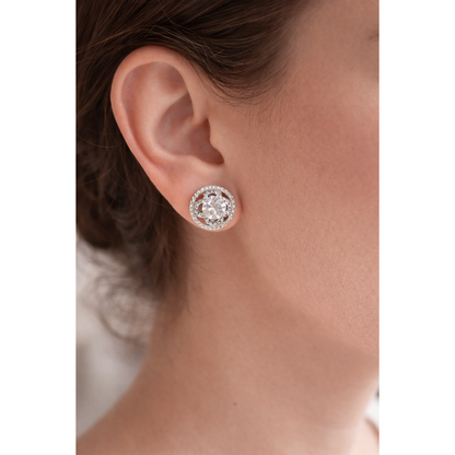 Close-up of TIAS crystal halo stud earrings worn on a model’s ear, highlighting size, brilliance, and elegant design.”