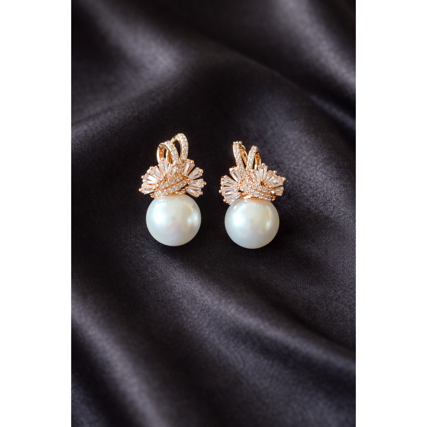 Elegant TIAS gold pearl earrings with sparkling crystal accents displayed on black satin fabric