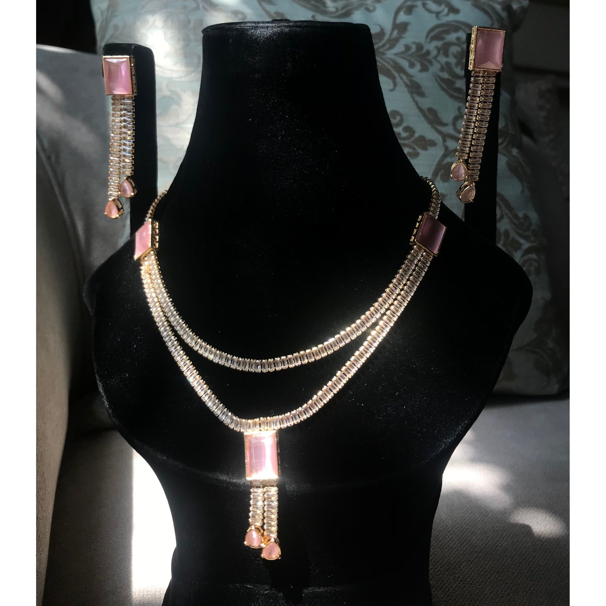 Necklace and earrings set on a black mannequin bust with a decorative background