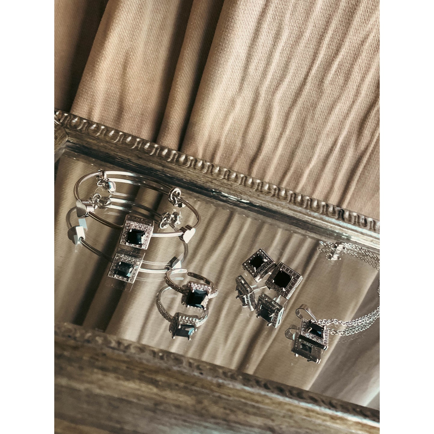 A complete silver-tone jewelry set including a flexible bracelet, a pair of stud earrings, and a necklace with a central pendant, all richly adorned with sparkling clear cubic zirconia stones, displayed on a white background.