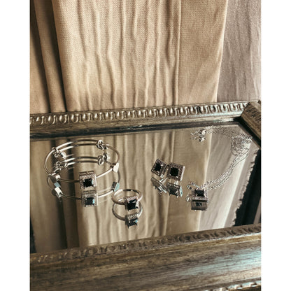 A complete silver-tone jewelry set including a flexible bracelet, a pair of stud earrings, and a necklace with a central pendant, all richly adorned with sparkling clear cubic zirconia stones, displayed on a white background.