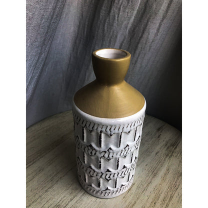 A two-tone ceramic vase with a gold top and a white bottom featuring a dark-outlined embossed quatrefoil pattern.