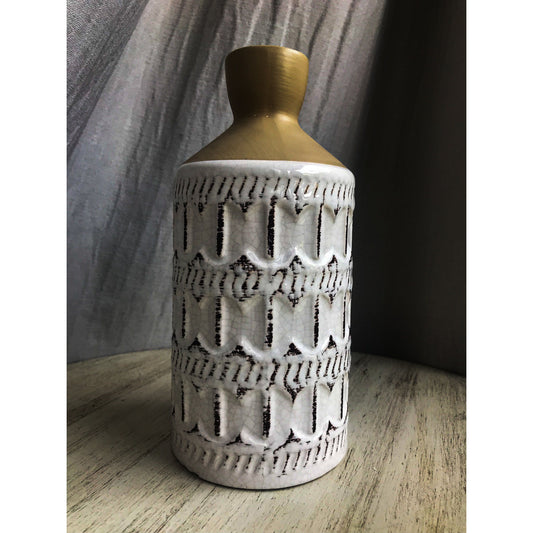 A two-tone ceramic vase with a gold top and a white bottom featuring a dark-outlined embossed quatrefoil pattern.