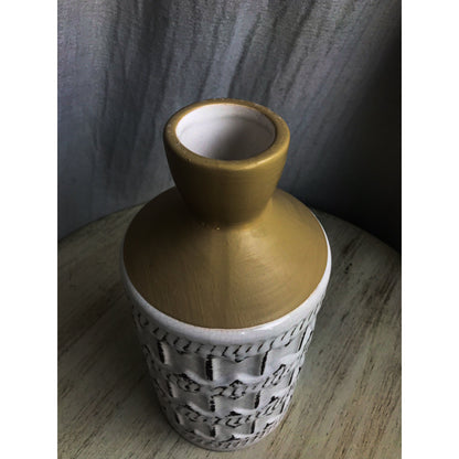A two-tone ceramic vase with a gold top and a white bottom featuring a dark-outlined embossed quatrefoil pattern.