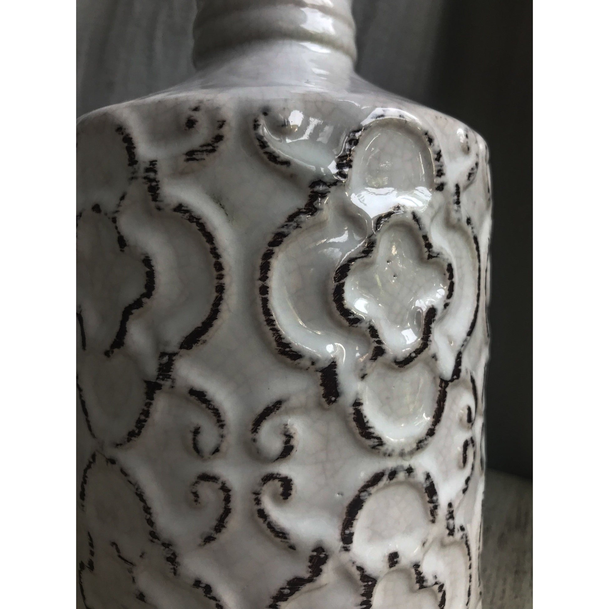 An ornate decorative vase with a classic urn shape, featuring intricate black metallic patterns on a white background