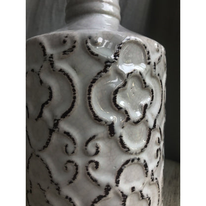An ornate decorative vase with a classic urn shape, featuring intricate black metallic patterns on a white background