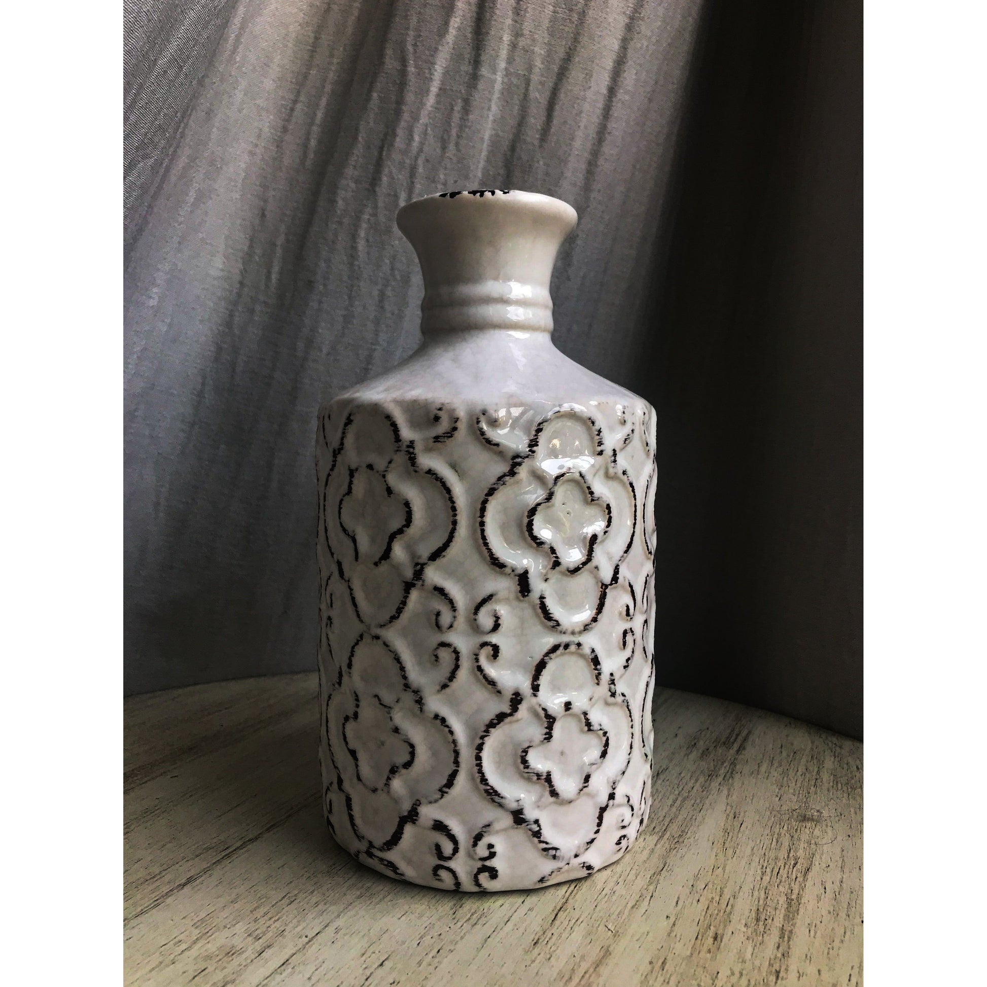 An ornate decorative vase with a classic urn shape, featuring intricate black metallic patterns on a white background