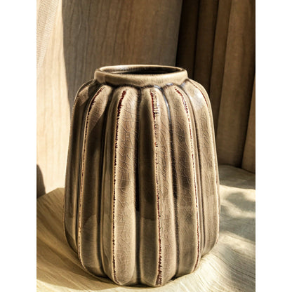 A grey ceramic vase with vertical fluting and a crackled glaze, shown empty and with dried branches inside.