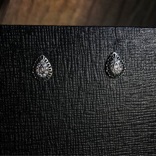 Silver teardrop-shaped stud earrings with crystal accents on a beige display stand