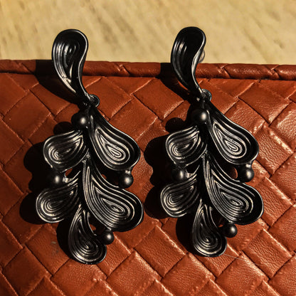 Two abstract drop earrings with swirling lines and small round accents, shown in silver, gold, rose gold, and black variations.