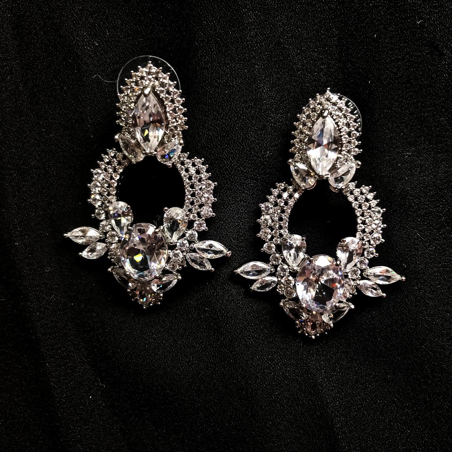 Two ornate silver-tone drop earrings featuring multiple clear marquise and oval-shaped sparkling stones, displayed against a black background.