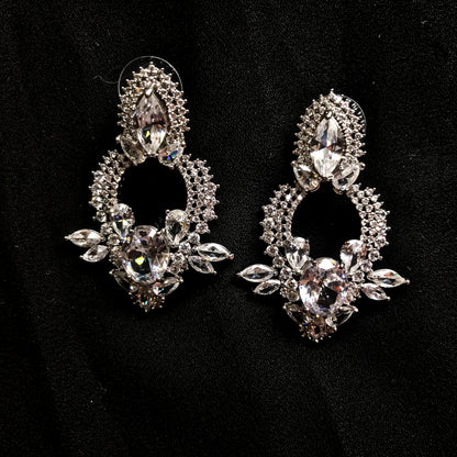 Two ornate silver-tone drop earrings featuring multiple clear marquise and oval-shaped sparkling stones, displayed against a black background.