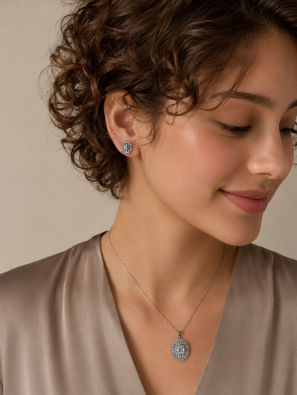 Woman wearing silver floral crystal pendant necklace and matching stud earrings with detailed circular design and sparkling stones.