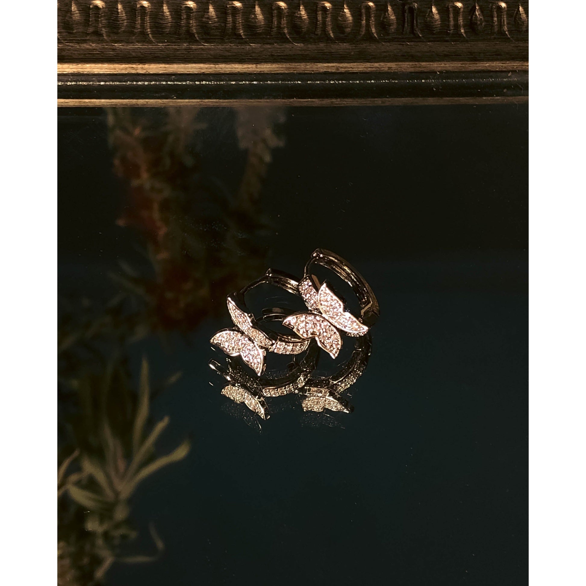 Two butterfly-shaped stud earrings, fully covered in sparkling clear stones.