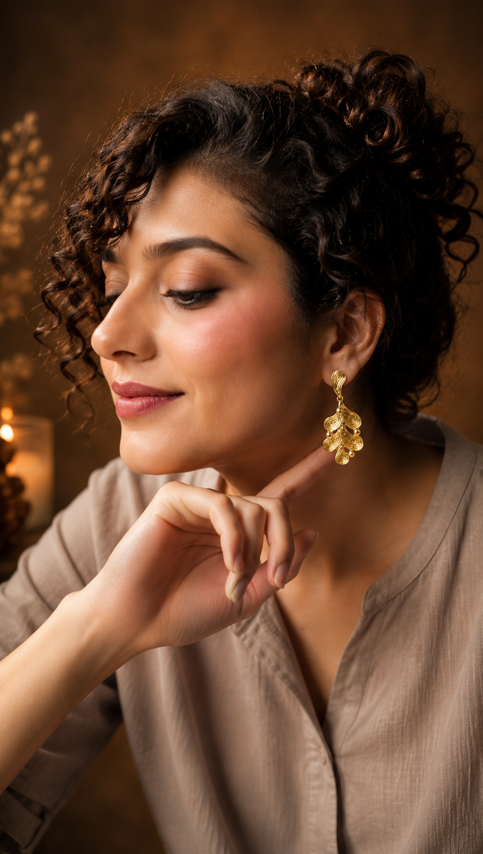 Woman wearing gold earrings with a warm, blurred background