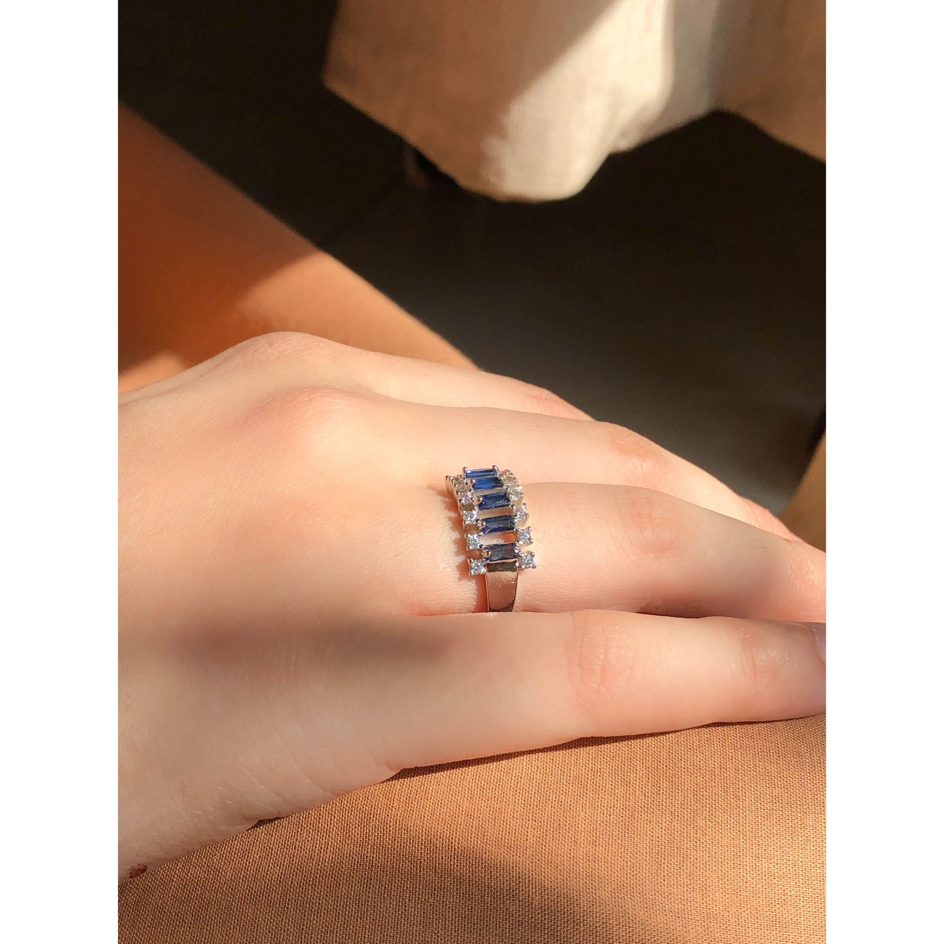A close-up of a glittering ring featuring a large central clear stone and a band entirely covered in multiple rows of smaller clear sparkling stones.