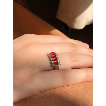 A close-up of a glittering ring featuring a large central clear stone and a band entirely covered in multiple rows of smaller clear sparkling stones.