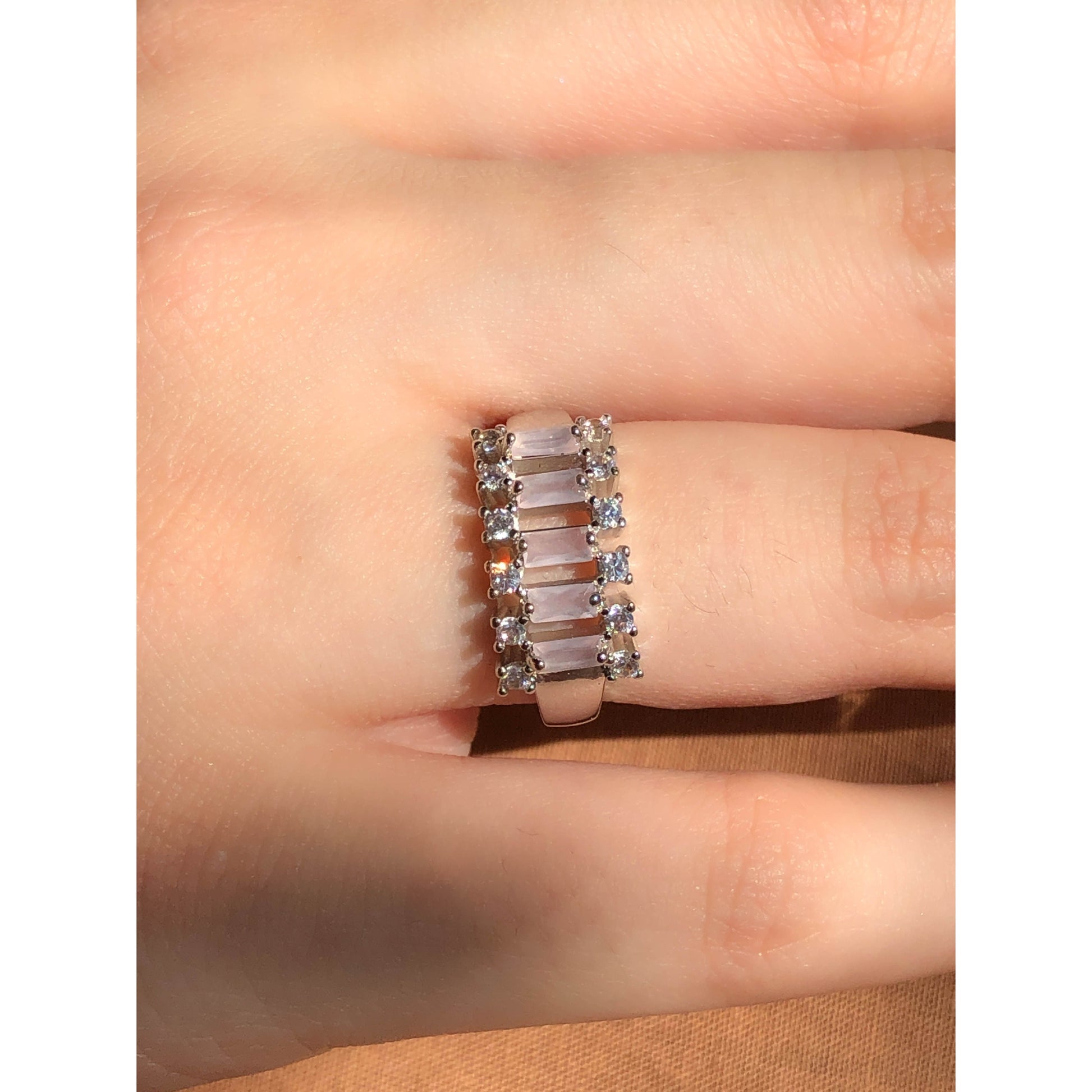 A close-up of a glittering ring featuring a large central clear stone and a band entirely covered in multiple rows of smaller clear sparkling stones.