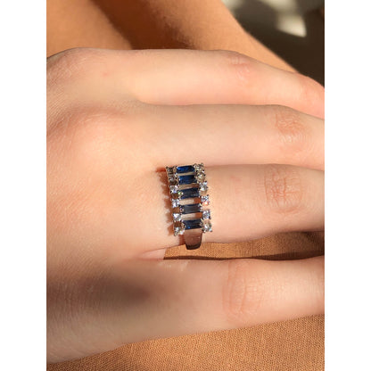A close-up of a glittering ring featuring a large central clear stone and a band entirely covered in multiple rows of smaller clear sparkling stones.