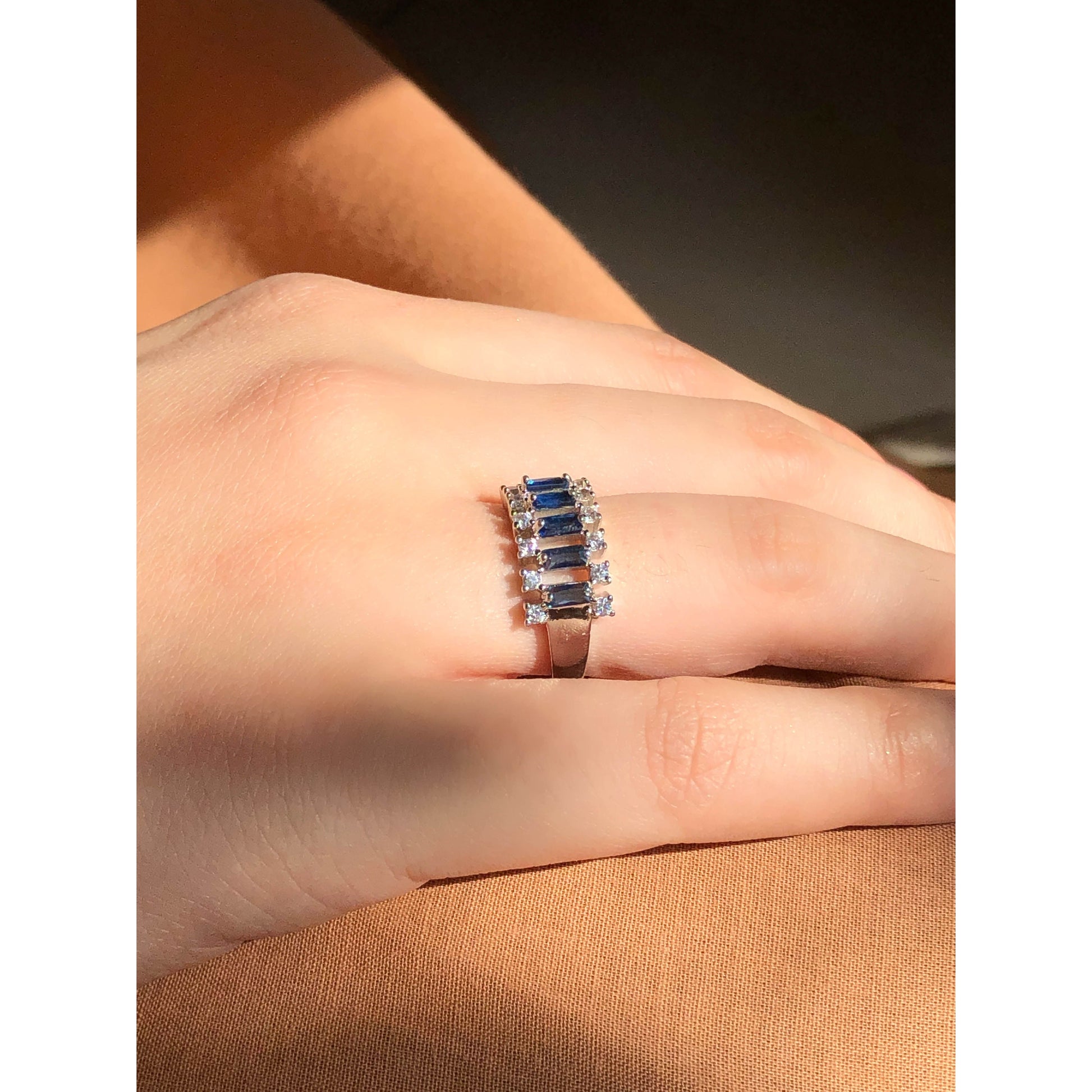A close-up of a glittering ring featuring a large central clear stone and a band entirely covered in multiple rows of smaller clear sparkling stones.
